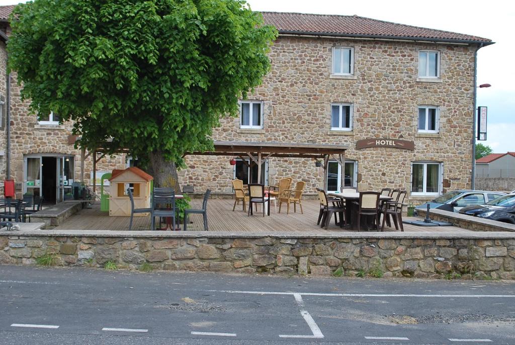 a building with tables and chairs in front of it at Hôtel Des Voyageurs in Bellevue-la-Montagne