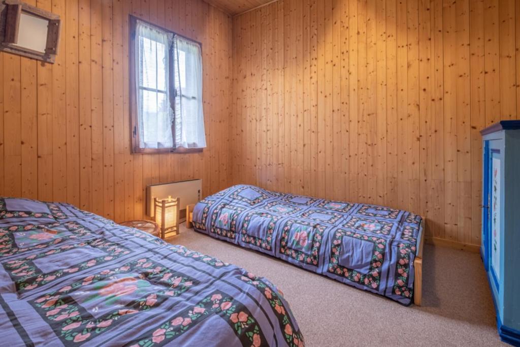 two beds in a room with wooden walls and a window at Family chalet with sublime views of Mont Blanc in Chamonix