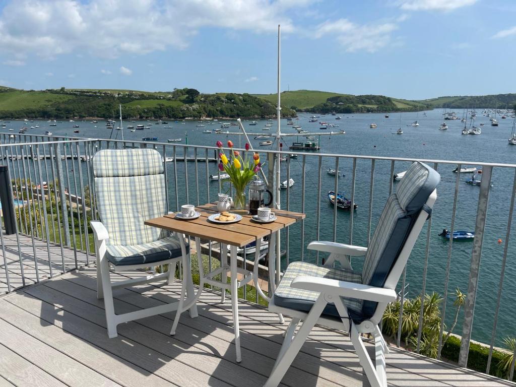 einen Tisch und Stühle auf einer Terrasse mit Blick auf das Wasser in der Unterkunft 36 The Salcombe in Salcombe