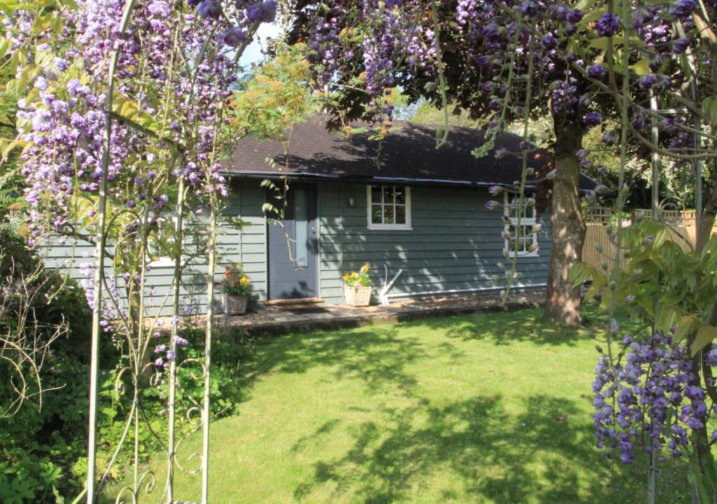 a small blue house with a yard with purple flowers at Garden Lodge in Worlingworth