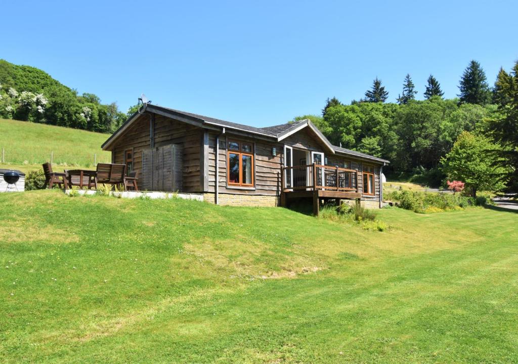 uma cabana de madeira numa colina com um campo verde em Meadow Lodge - Cornwall em Cardinham