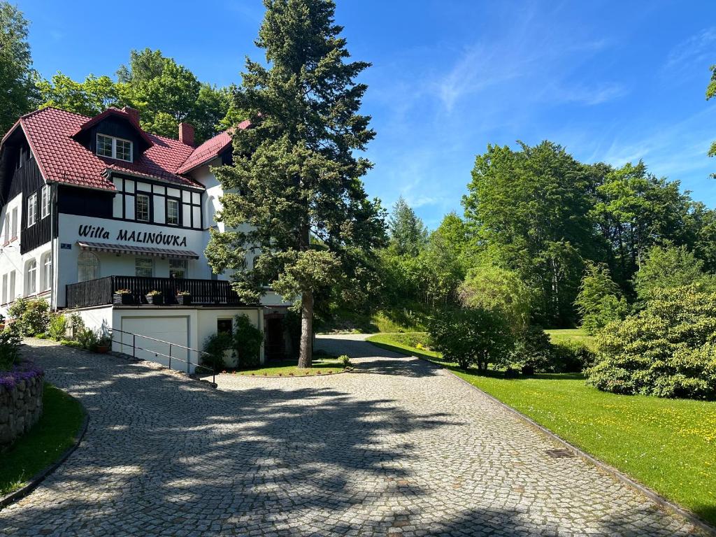 a driveway leading to a white mansion with a tree at Willa Malinówka - ogród wypoczynkowy z widokiem na Śnieżkę in Karpacz