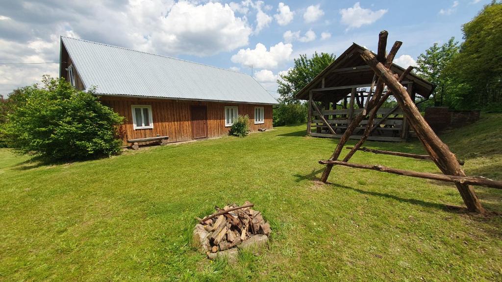 a log cabin in a yard with a pile of wood at Wierzchowina Relax & Reset in Łęki Dolne