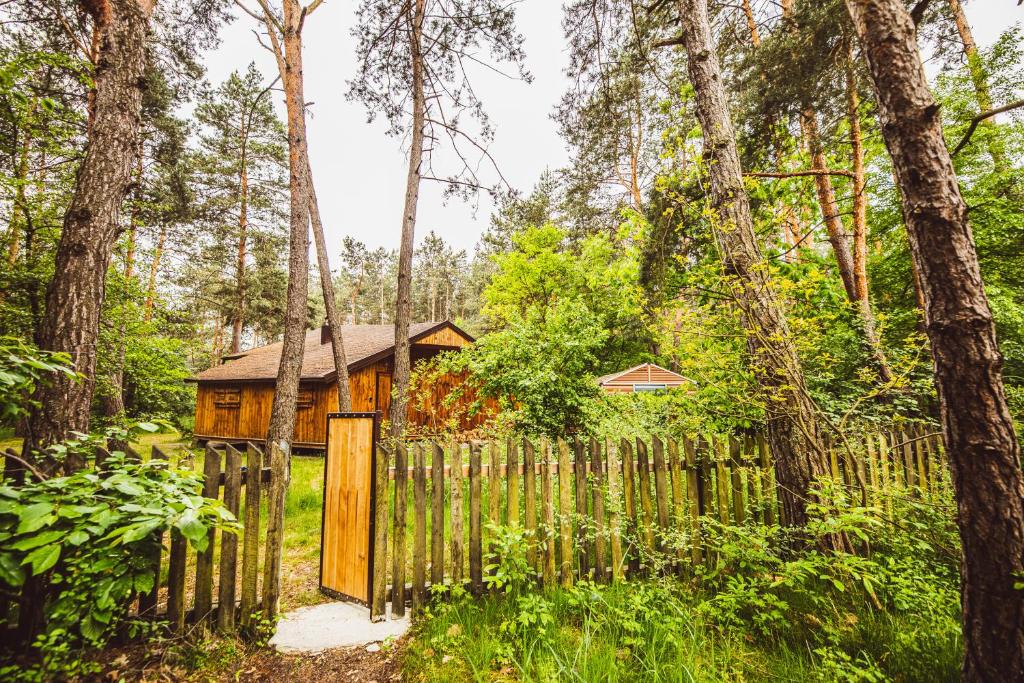 a wooden fence in front of a cabin in the woods at Cozy Nature Retreat with Patio Fireplace Garden 