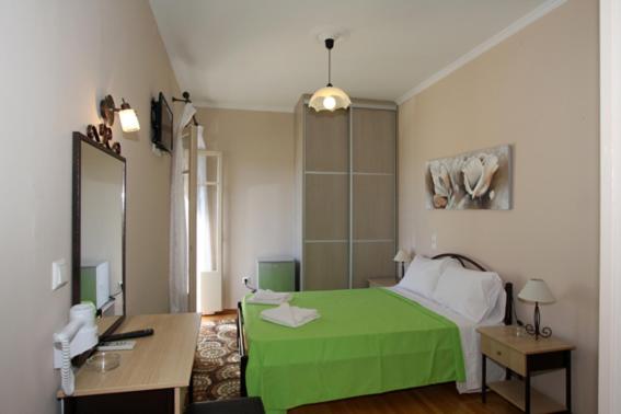 a bedroom with a green bed and a desk at Lefcothea Guest Rooms in Lákka