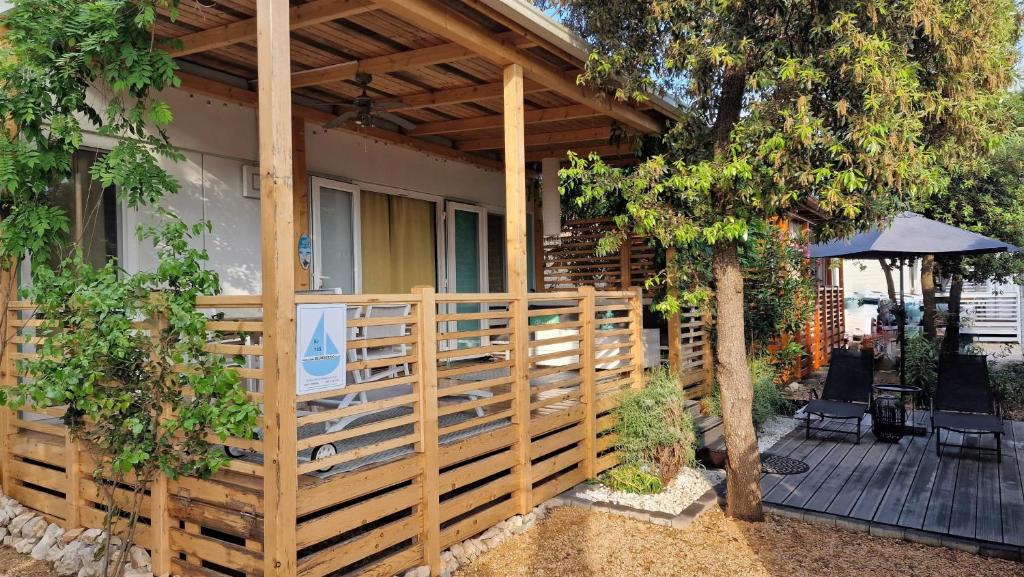 a wooden fence in front of a house with an umbrella at Mobile Home BelDesiderio Soline in Biograd na Moru