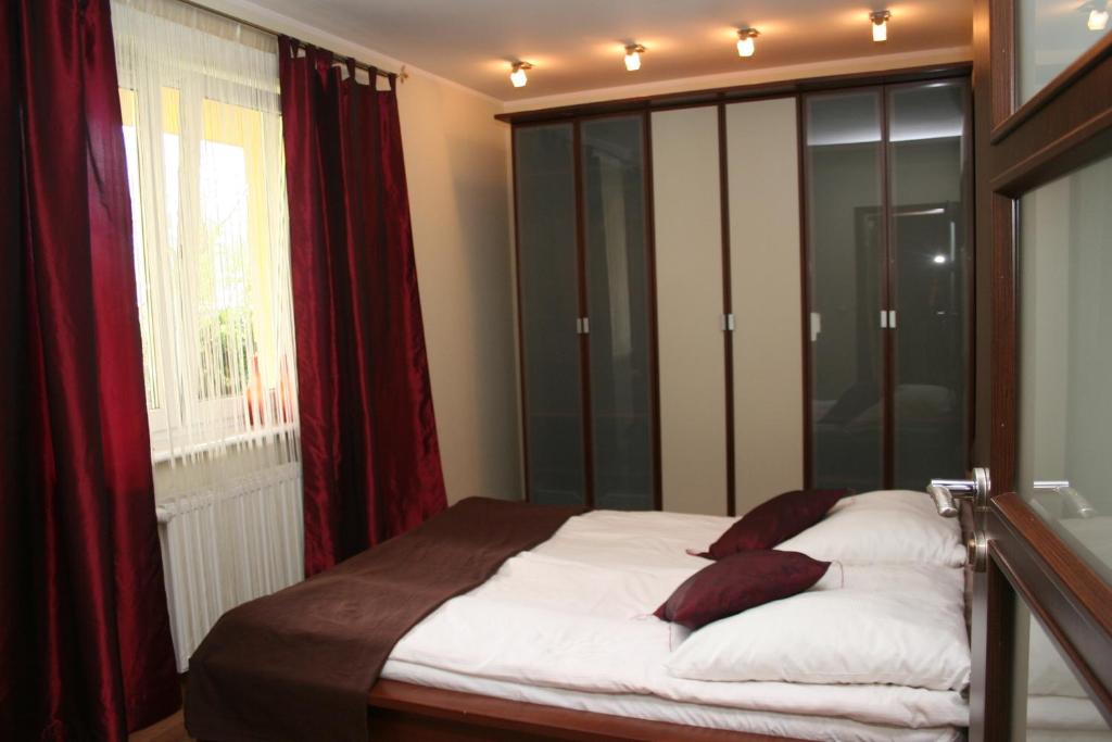 科沃布熱格的住宿－Kołobrzeg Apartament，一间卧室配有一张带红色窗帘的床和一扇窗户