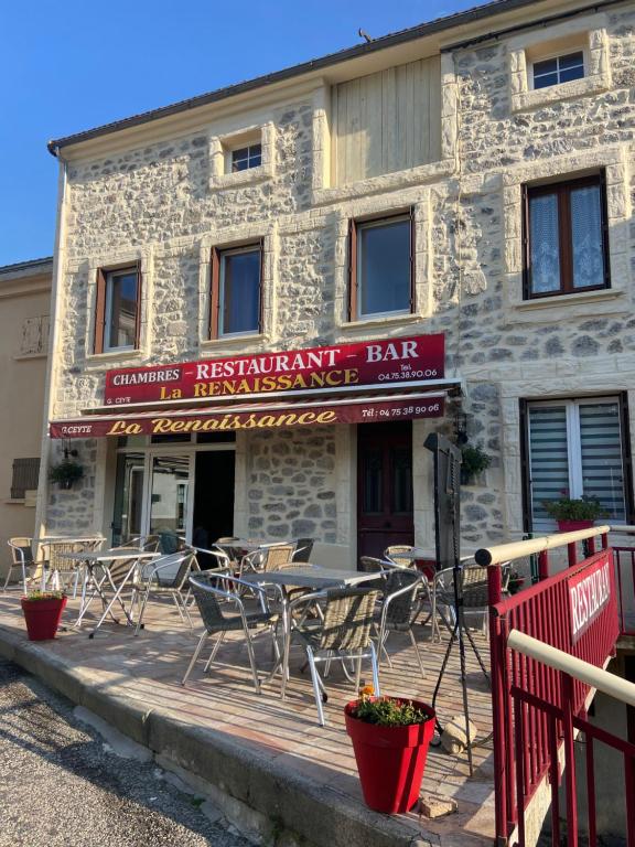 un restaurante con mesas y sillas frente a un edificio en La renaissance, en Saint-Cirgues-en-Montagne