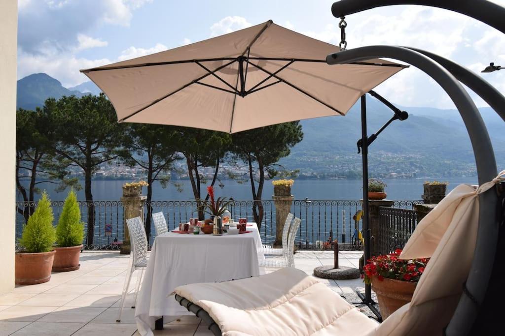 un patio con mesa y sombrilla en Appartamento Belle Epoque vista lago en Onno