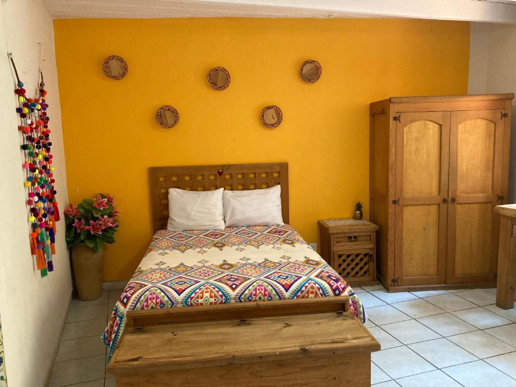 1 dormitorio con cama y pared amarilla en Cálida habitación a 10 min de Santo Domingo en Oaxaca de Juárez