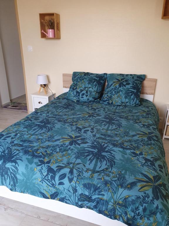 - un lit doté d'un couvre-lit bleu avec des palmiers dans l'établissement CHEZ PILOU, à Varennes-sur-Allier