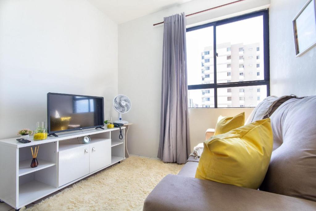 een woonkamer met een bank en een tv bij Condomínio Ibiza #703 - Apartamento na Praia de Candeias por Carpediem in Recife