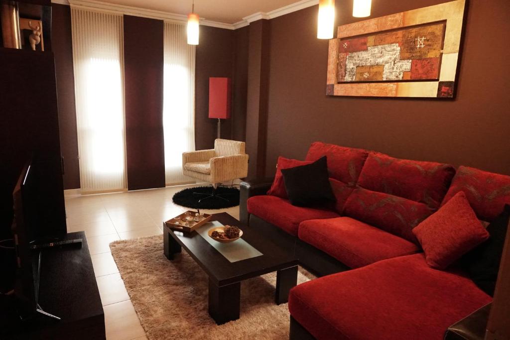 a living room with a red couch and a table at Piso Alerín in Silleda