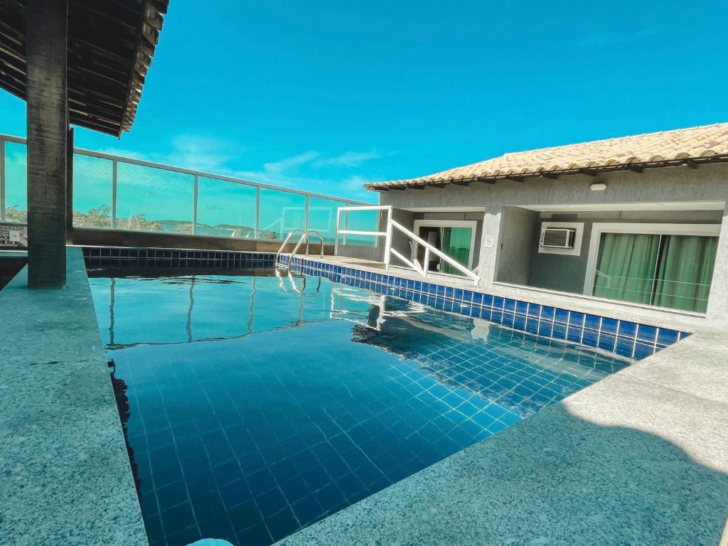 una piscina junto a una casa con azulejos azules en Pousada São Pedro en São Pedro da Aldeia