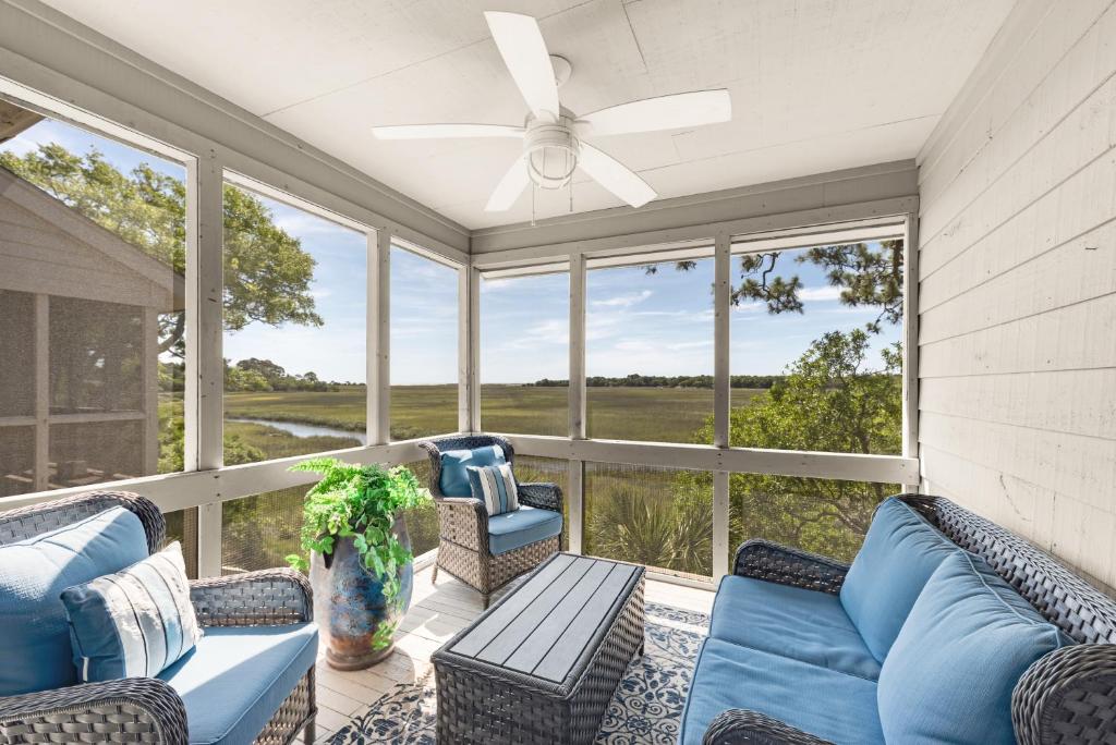 a screened in porch with blue furniture and windows at 1235 Creekwatch Villa in Seabrook Island