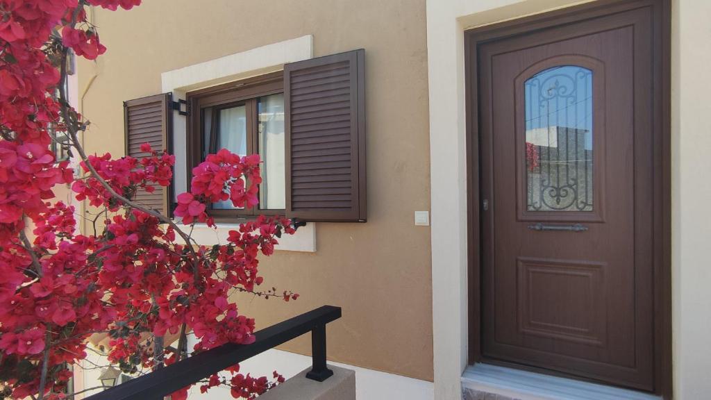 una casa con una puerta marrón y flores rojas en Rodea Sunrise en Rodhiá