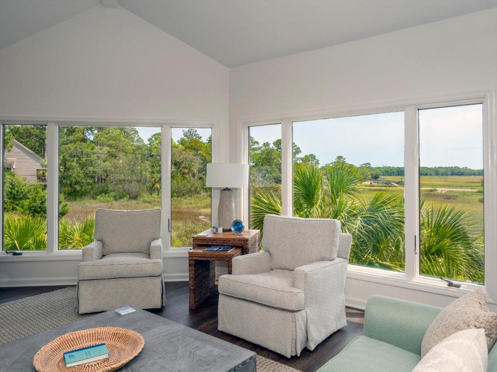 a living room with two chairs and a table and windows at 1515 Deer Pointe Villa in Seabrook Island