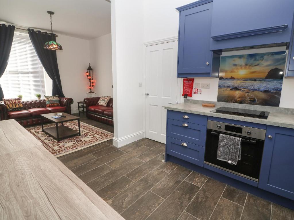 a kitchen with blue cabinets and a living room at Meneage House in Helston