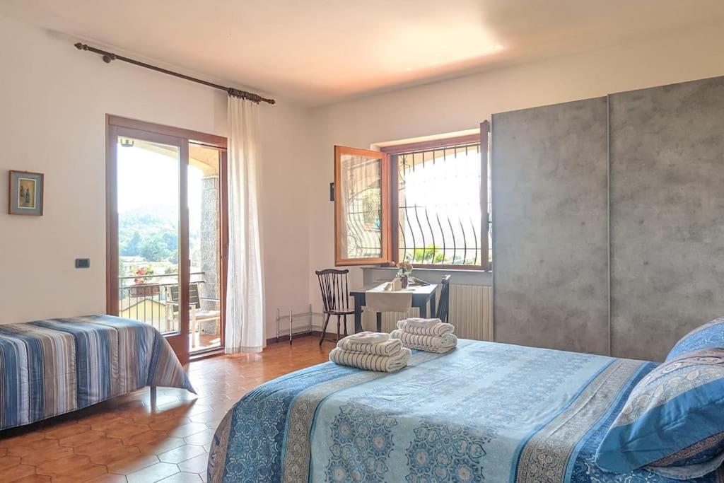 una camera con due letti, un tavolo e una finestra di Villa Le Arcate zona Lago Maggiore a Cittiglio