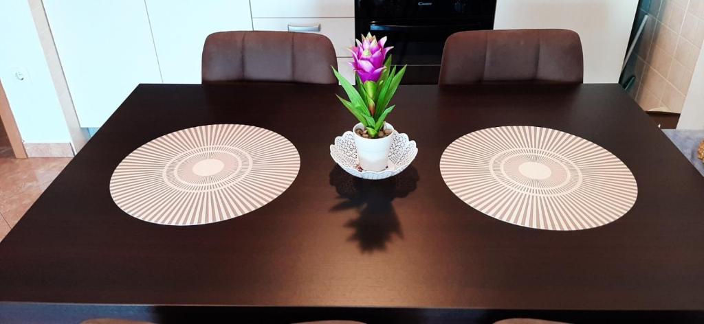 a table with two plates and a vase with a flower on it at Apartment RB in Omišalj