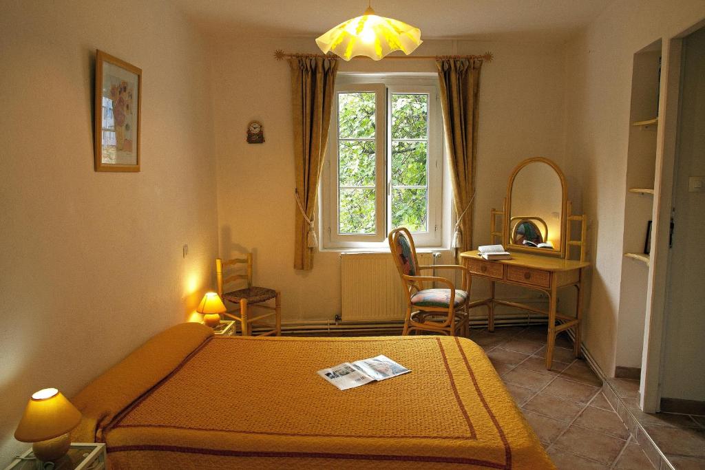 a bedroom with a bed and a desk and a window at Moulin De Cornevis Bed and Breakfast in Privas
