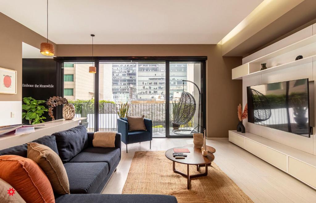 a living room with a blue couch and a tv at Casa Magenta by Kukun in Mexico City