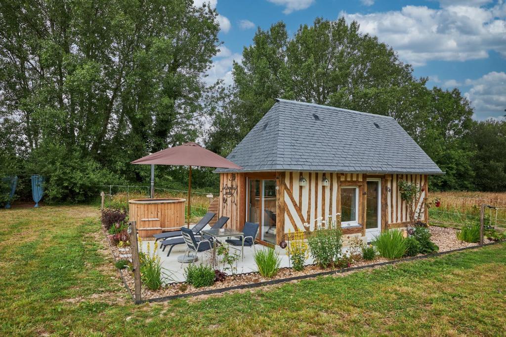 a log cabin with a patio and an umbrella at Le chouette insolite in Cresseveuille