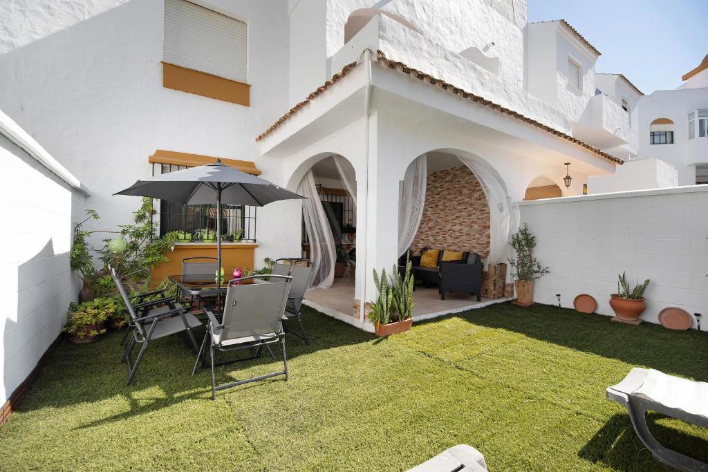 een patio met een parasol en een tafel en stoelen bij Apartaclub la Barrosa in Chiclana de la Frontera