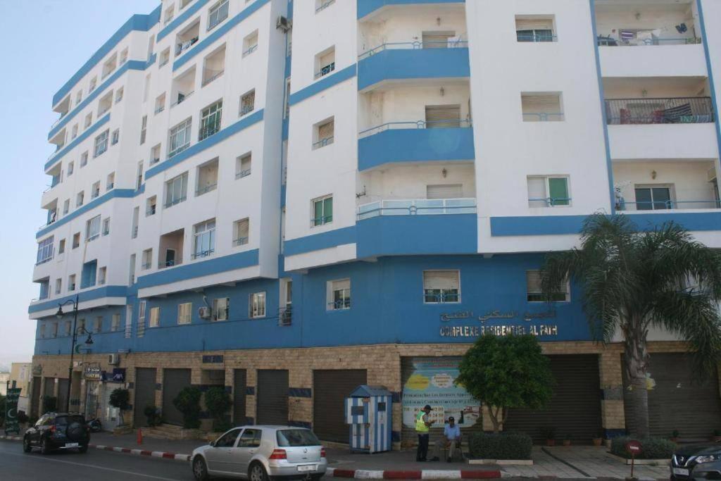 een blauw-wit gebouw met auto's voor het gebouw bij view apartments larache in Larache