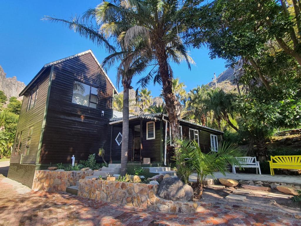 a small house with a palm tree in front of it at Varswaterkloof Houthuis in Paarl