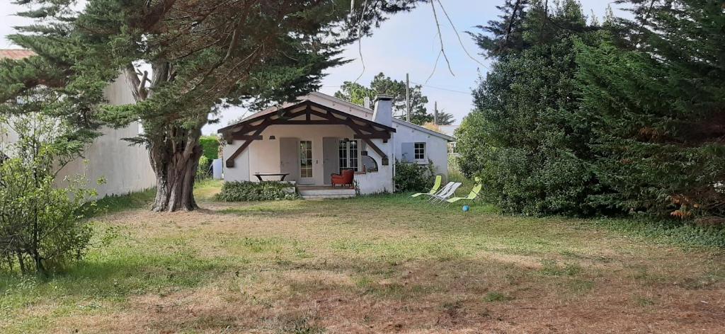 una pequeña casa blanca con un árbol y un patio en Jolie villa avec jardin à proximité de la plage, en La Brée-les-Bains