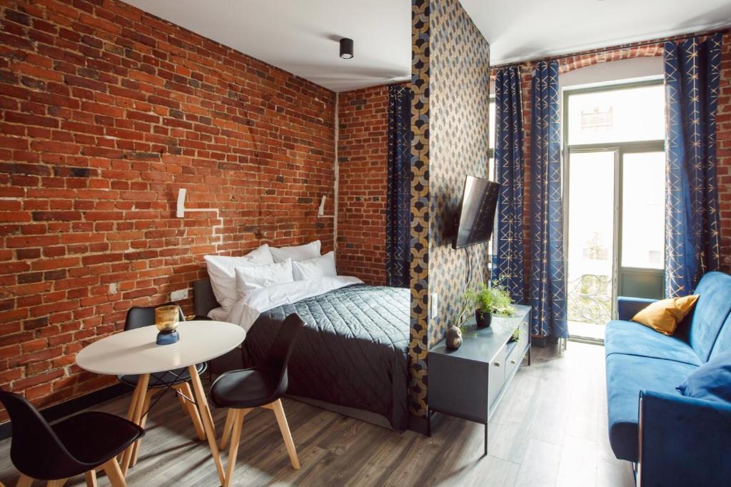 Cette chambre dispose d'un lit et d'un mur en briques. dans l'établissement East Street Apartamenty, à Łódź