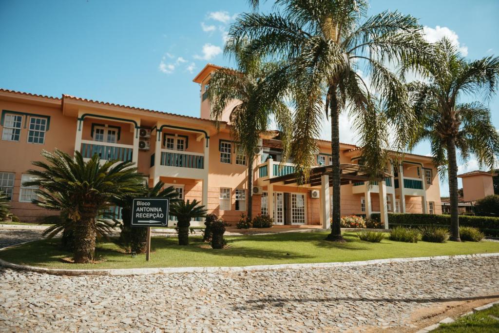 a building with palm trees in front of it at Engenho da Serra Hotel EcoResort in Capitólio
