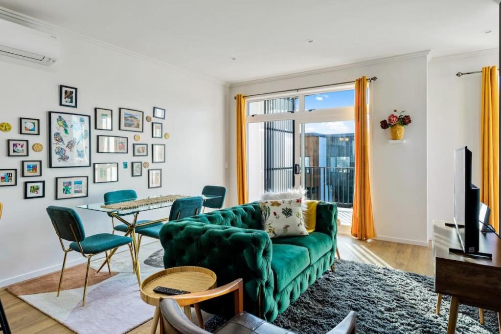 a living room with a green couch and a table at 3 Bedroom Stunner in Hobsonville - WiFi - Netflix in Auckland
