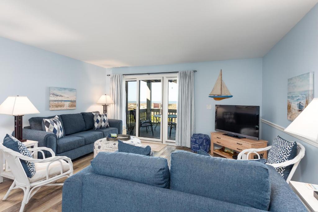 a living room with blue couches and a tv at 1305 Pelican Watch Villa in Seabrook Island