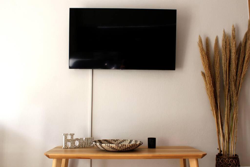un televisor colgado en una pared sobre una mesa en inHeart Apartment Chios en Chios