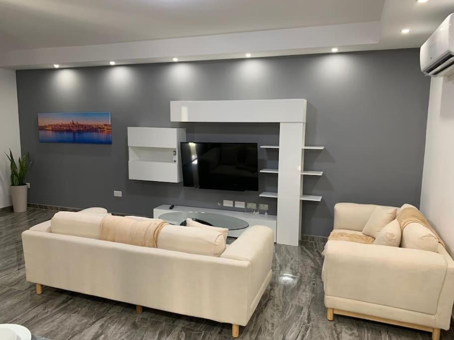 a living room with two white couches and a tv at Spacious lovely apartment in Mġarr 1 in Mġarr