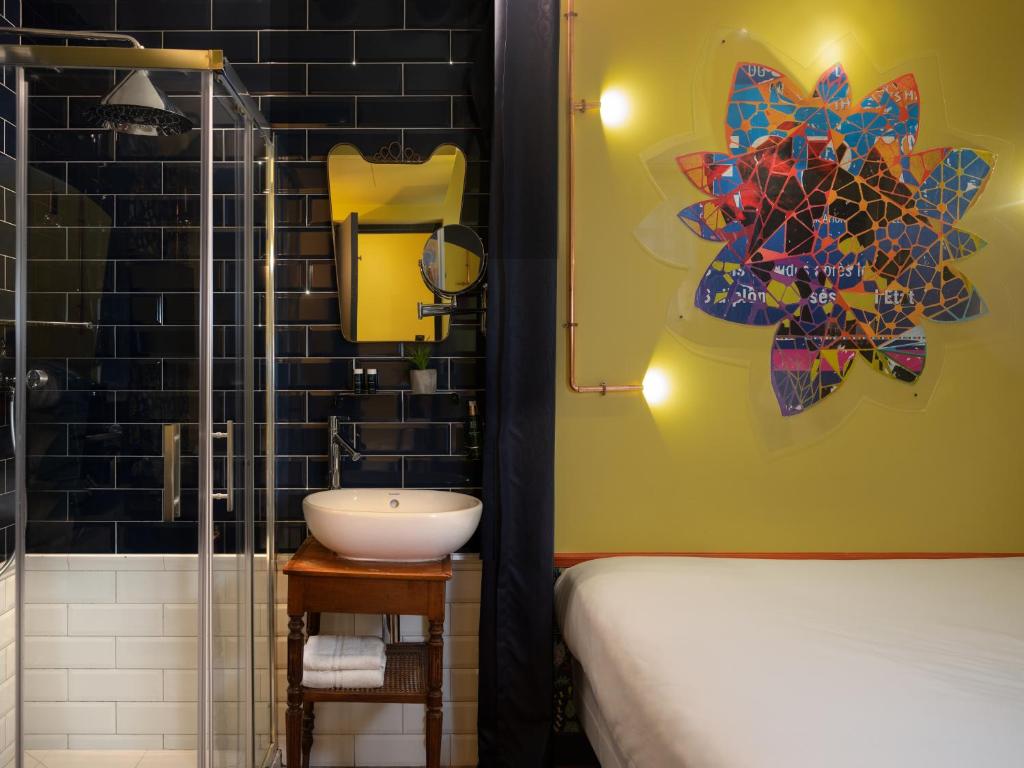 W łazience znajduje się umywalka i prysznic. w obiekcie Hôtel Exquis w Paryżu