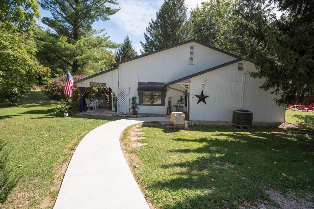 a white barn with a flag and a sidewalk at Harper Valley Cottage in Nashville