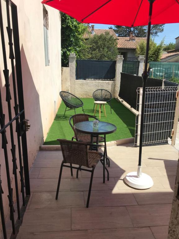 un patio avec une table, des chaises et un parasol dans l'établissement Studio cosy avec jardin proche centre et plage, à Montpellier