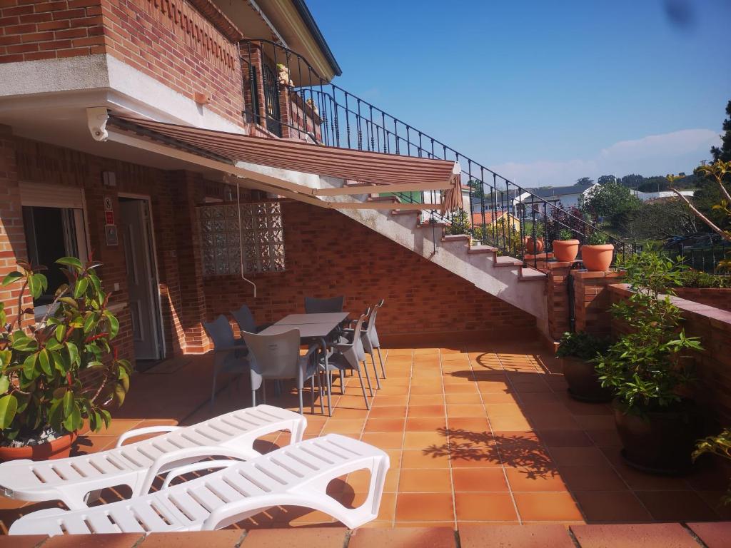 un patio con sillas blancas, una mesa y escaleras en APARTAMENTO COSTA CANTABRIA, en Cuchía