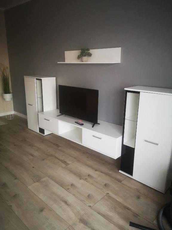 ein Wohnzimmer mit weißen Möbeln und einem Flachbild-TV in der Unterkunft Urokliwy apartament in Sandomierz
