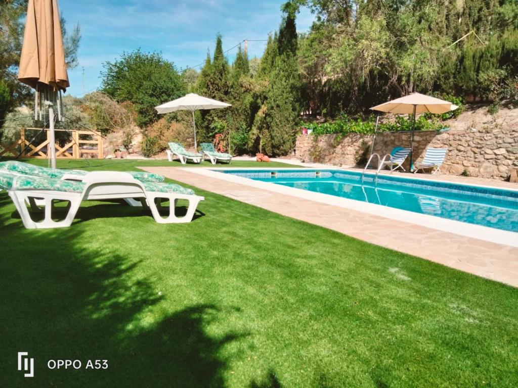 una piscina con sillas y sombrillas en un patio en Casa el Tío Enrique, en Cazorla