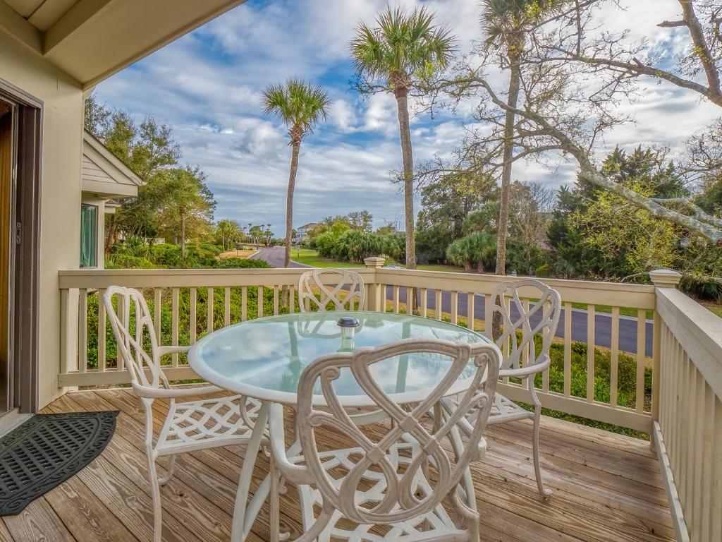 a table and chairs on a deck with palm trees at 724 Spinnaker Beach Villa in Seabrook Island