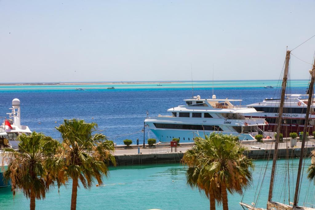 two boats docked at a dock with palm trees at The Bay Hotel Hurghada Marina in Hurghada