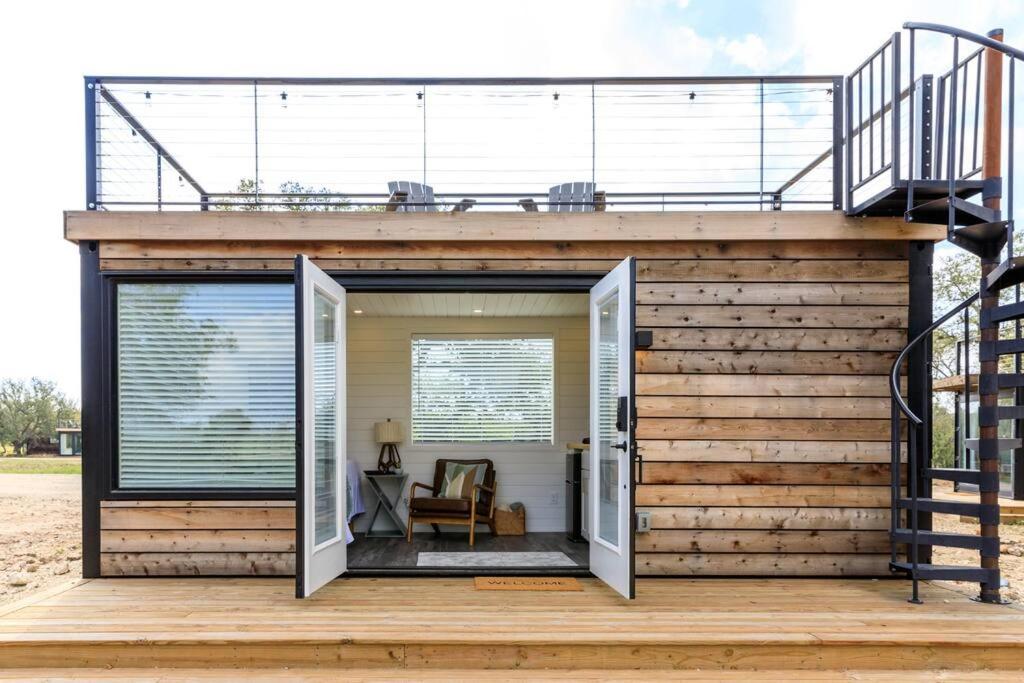 ein winziges Haus mit einer Terrasse und einer Treppe in der Unterkunft New The Sunset Luxury Container Home in Fredericksburg