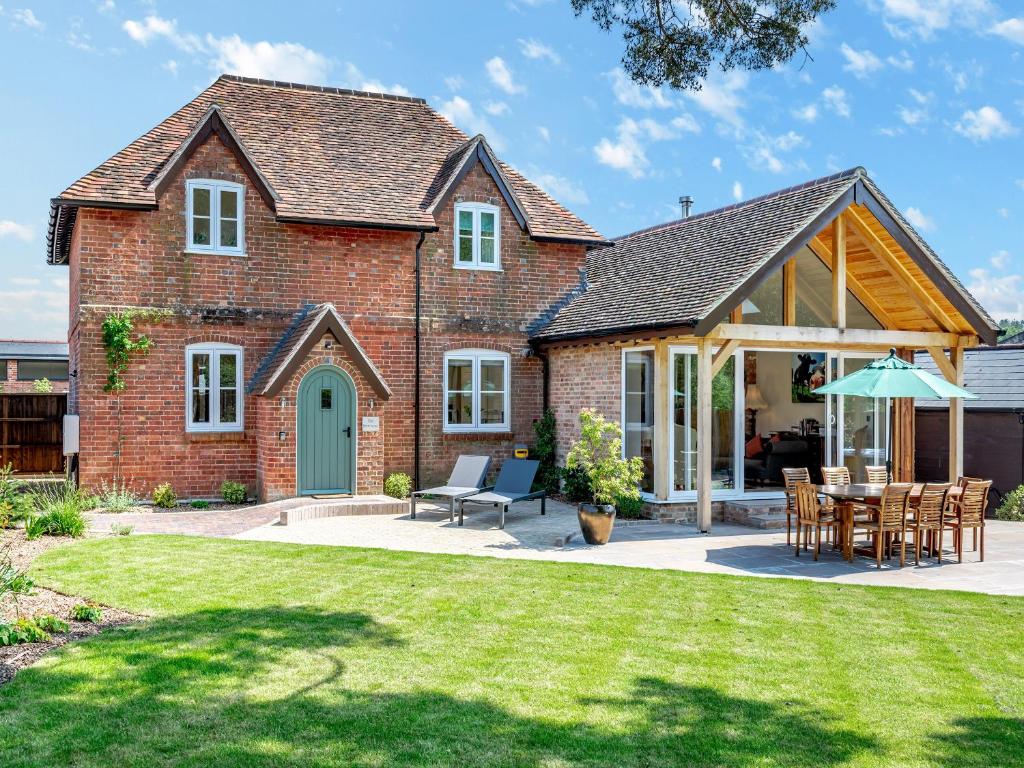 een stenen huis met een tafel en stoelen in een tuin bij The Farmhouse in Ferndown