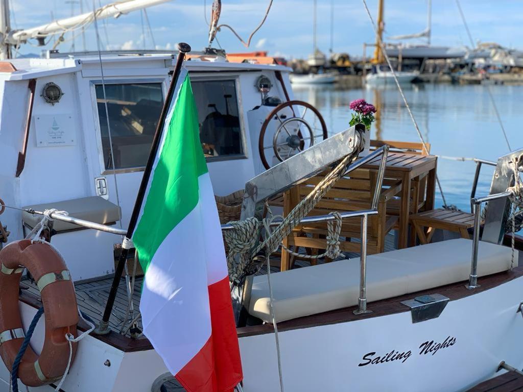 a boat with a flag and a table on it at Sailing Nights Boat&breakfast in Alghero