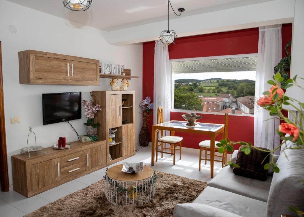 ein Wohnzimmer mit einem Sofa und einem Tisch mit einem TV in der Unterkunft Antoxos Sacra Home I in Chantada
