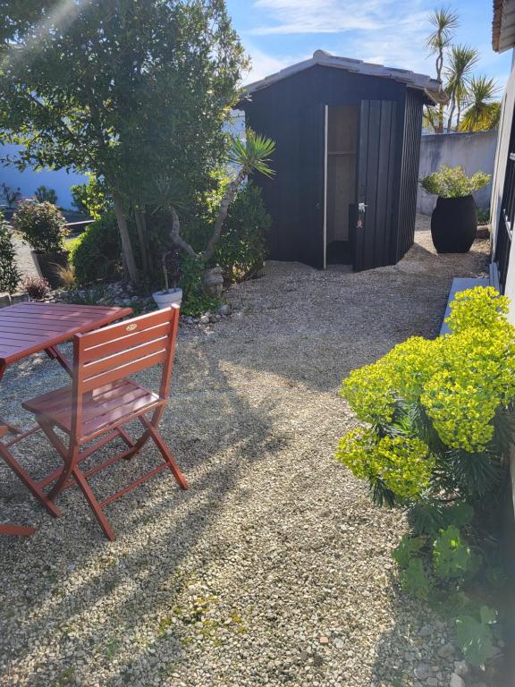 a bench and a table in a garden with a shed at Ma Chambre d'Amis in Saint-Clément-des-Baleines